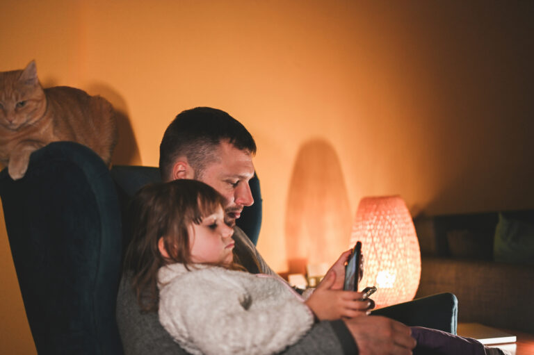father with daughter relaxing with mobile phone
